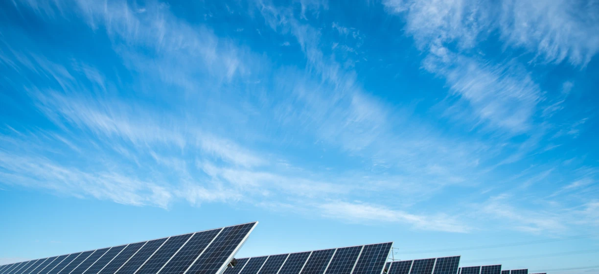 Błękitna tablica słoneczna pod dziennym słońcem, wydobywająca energię słoneczną w efektywny sposób. Innowacyjna technologia przechwytująca światło słoneczne pomimo kilku chmur na niebie.
